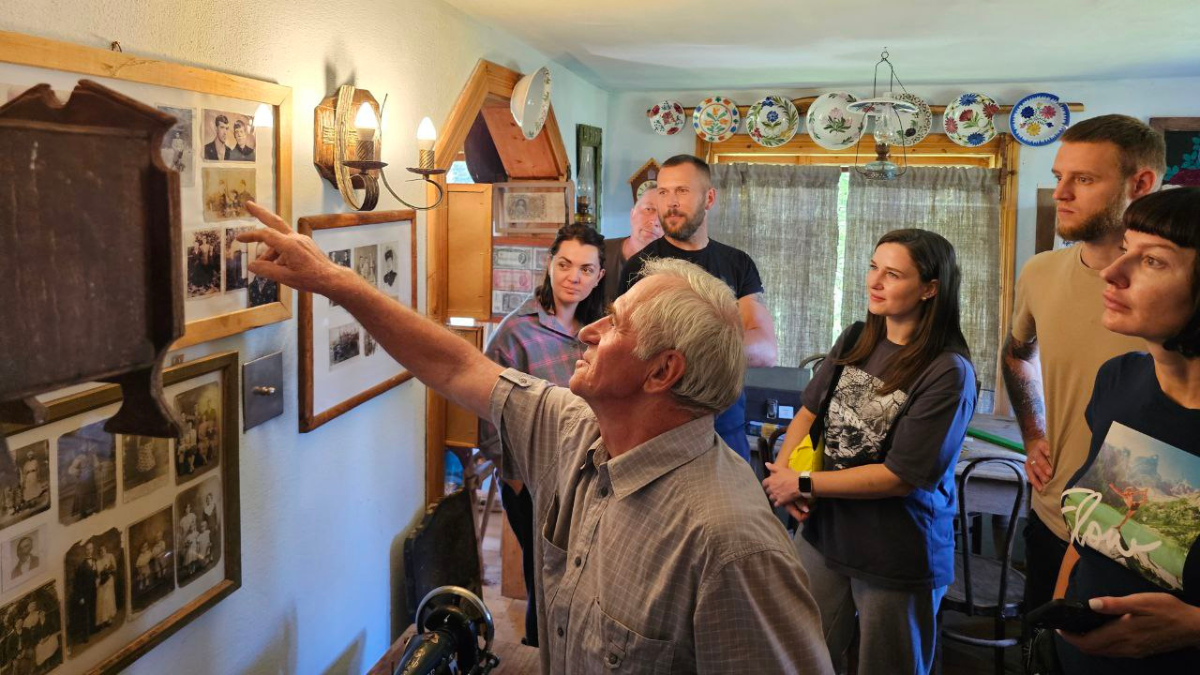 Туристи всередині музею села Топільське розглядають старі фотографії